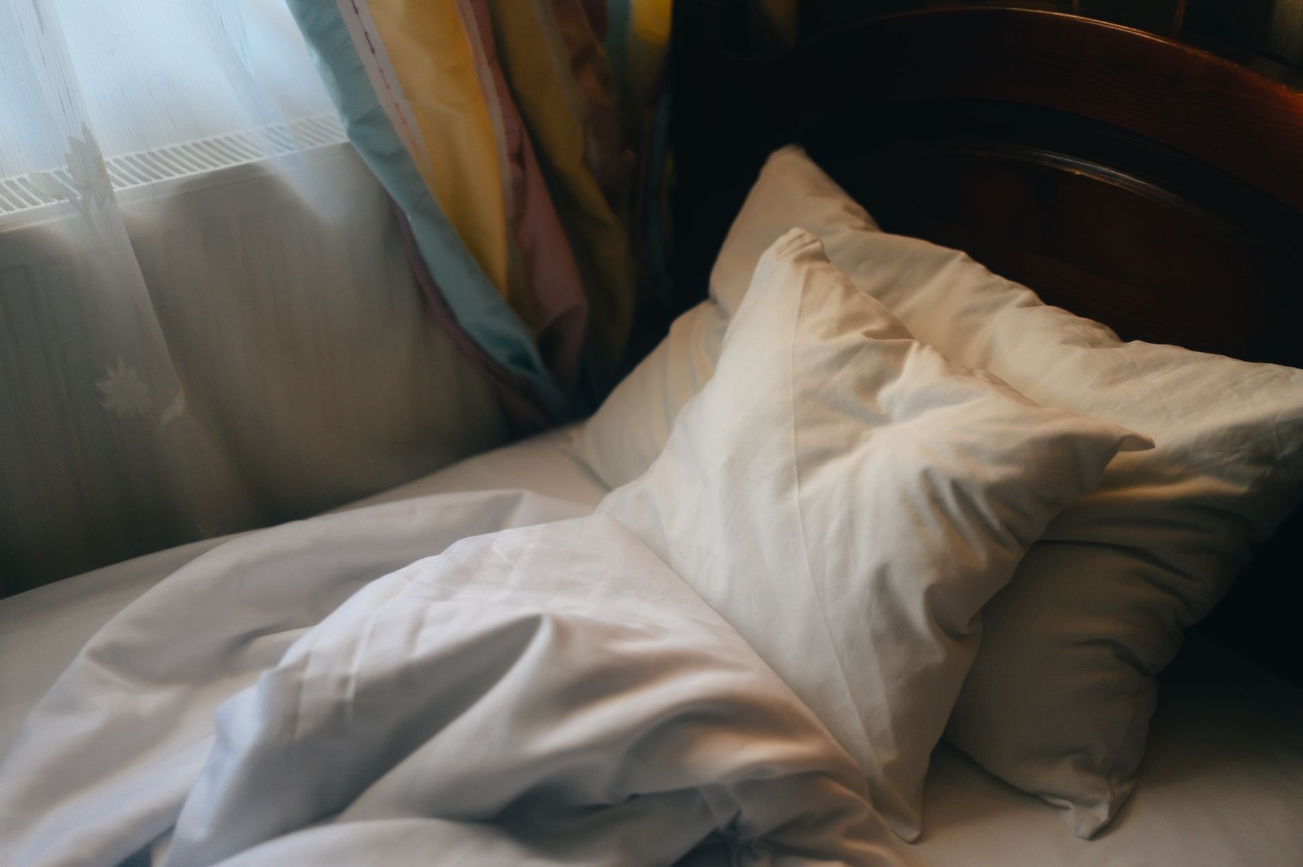 Inviting unmade bed with soft pillows in morning light